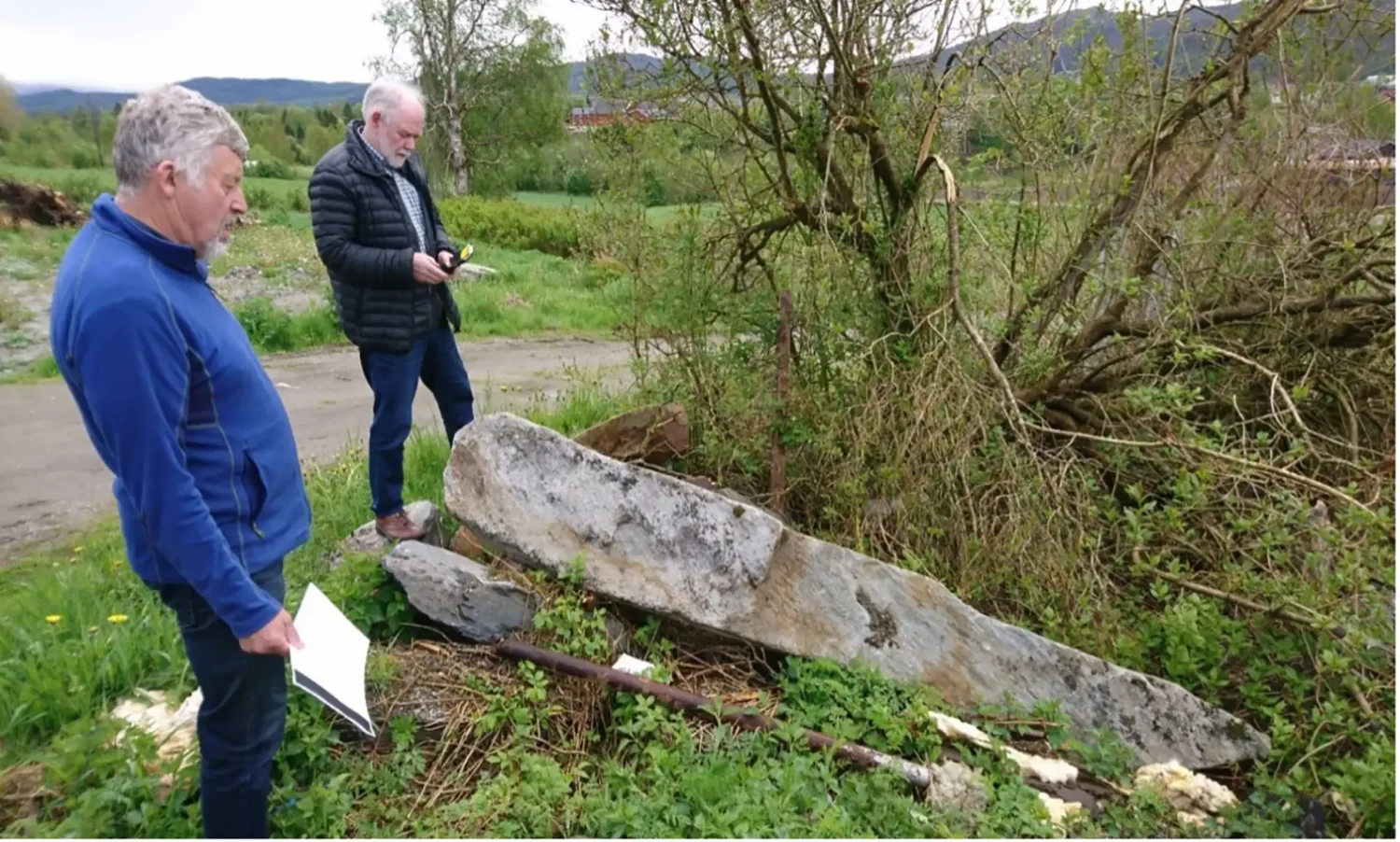 Befaring sommer 2019 av bautasteinene der de lå på gården Lauvli med Carl Ivar Storøy og Magne Rønning (nærmest), tidligere eier av Lauvli. Foto: Brynjar Mørkved