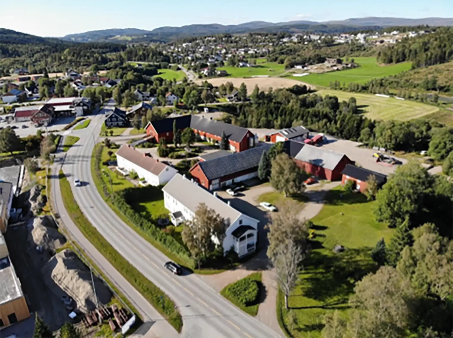 Hunnagårdene (2021) - Hunn Østre (nærmest) uten butikk-/bakeribygninga og Hunn Vestre uten buret (nå: Koltjønnhytta). Lauvli og boligfelt vest i Hunnaåsen i bakgrunnen. Foto: Sverre Rygh.